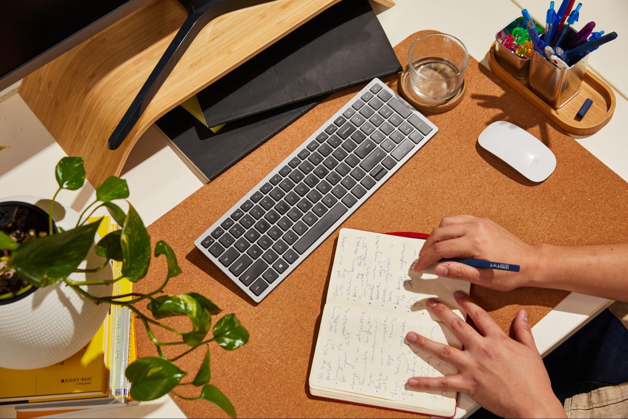 woman writing in her notebook in front of the computer