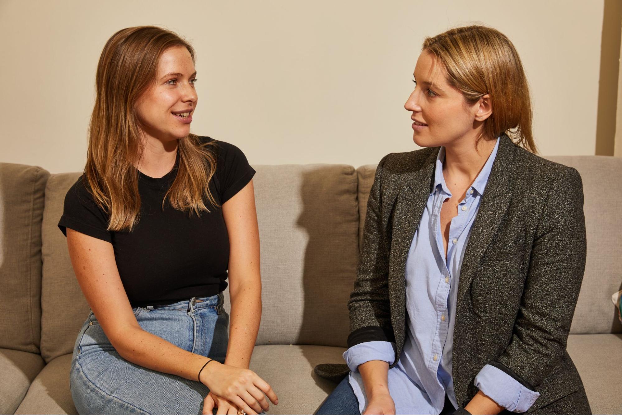 two employees seated on a couch and chatting to each other