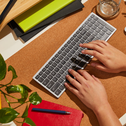 Two hands typing on a wireless keyboard.
