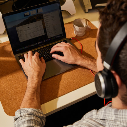 A man wearing headphones typing on his laptop.