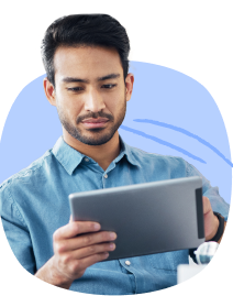 A man wearing blue collared top browsing on his tablet.