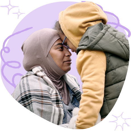 A woman in a hijab and a child in a hoodie touching foreheads affectionately.