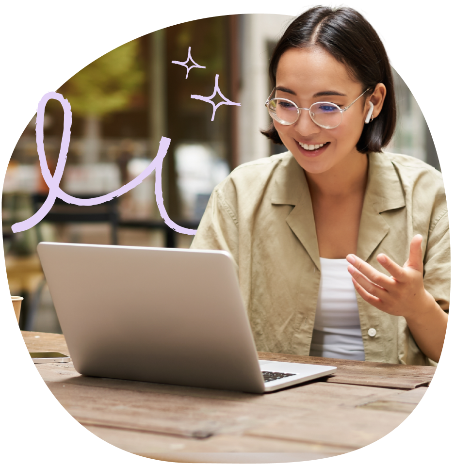 A woman wearing eyeglasses and a brown-collared top, smiling in front of her laptop.